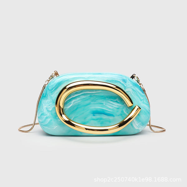 Kleine rechteckige Crossbody-Clutch mit abgerundeten Ecken, oversized poliertem C-förmigem Goldgriff und schmalem Goldkettenriemen, Detailansicht