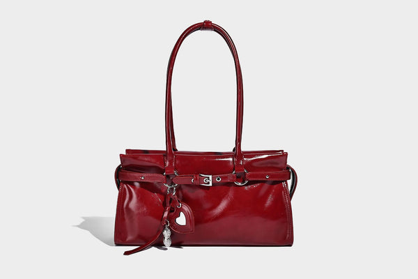 Structured rectangular glossy tote shoulder bag with belt buckle front strap and dangling charm hardware, detail view 15