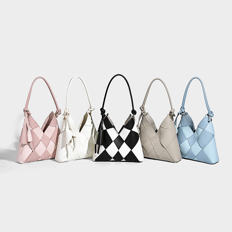 Compact bucket shoulder bag with black-and-white diamond patchwork panels, knotted top handle, gold-tone hardware, and