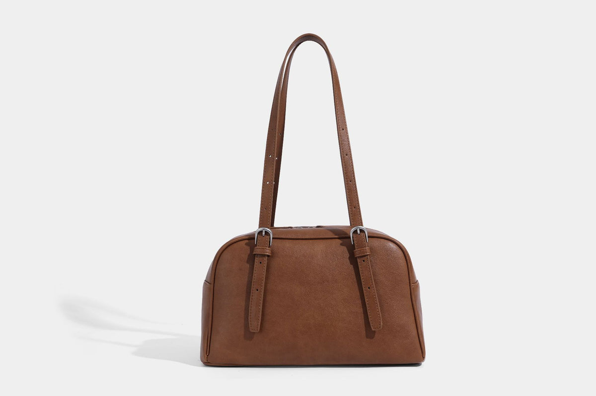 Structured dome-shaped shoulder bag with leather-look finish, top zipper closure, dual adjustable slim straps, and, detail