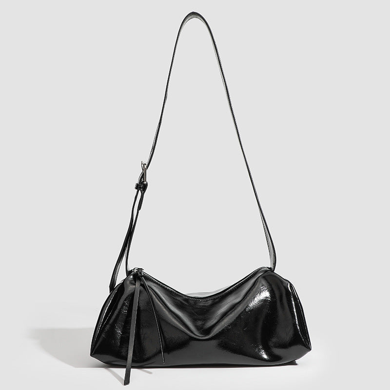 Black glossy leather-look slouchy shoulder bag with gathered top, zip tassel closure, and long adjustable silver-buckle