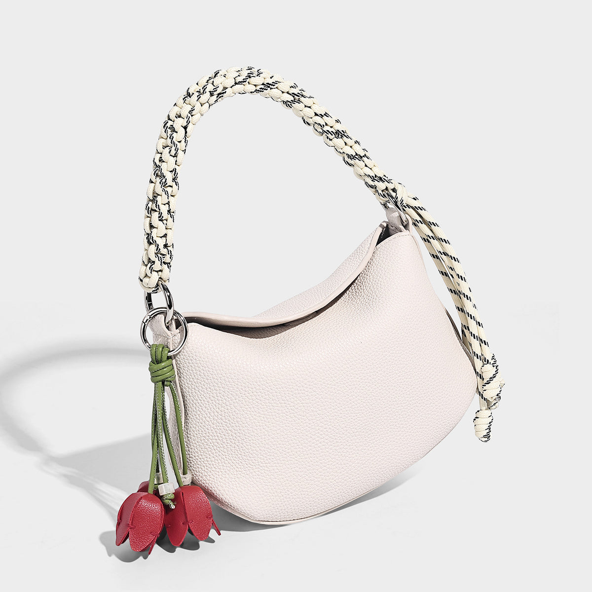 Small crescent half-moon bag in pebbled leather-look finish with braided top handle, silver-tone ring hardware, and, detail