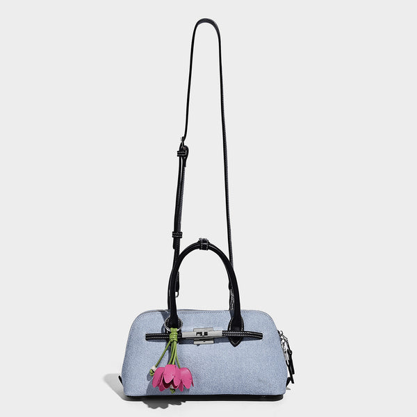 Compact structured satchel in light blue denim-look fabric with black leather-look trim, silver turn-lock closure, rolled