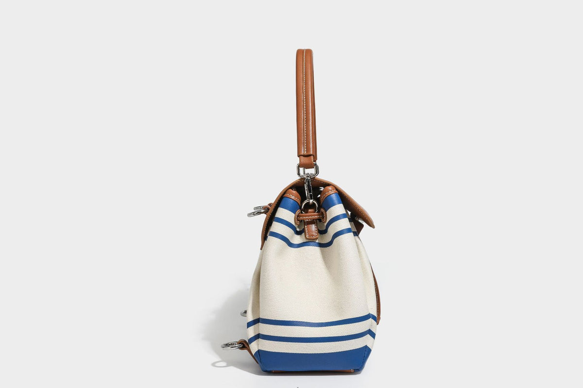 Cream canvas bucket bag with blue horizontal stripes, tan leather-look flap and trim, drawstring closure, silver-tone, detail
