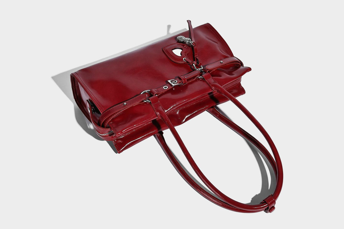 Structured rectangular glossy tote shoulder bag with belt buckle front strap and dangling charm hardware, detail view 19