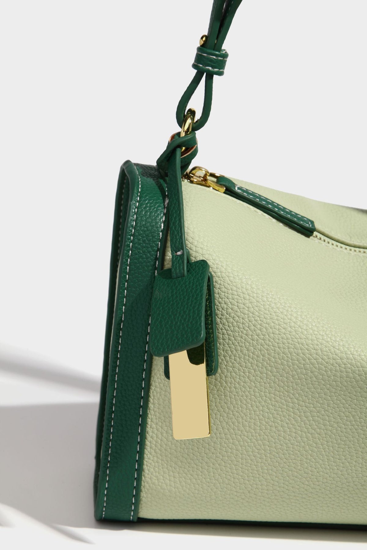 Structured two-tone shoulder bag with pebbled leather-look finish, contrast trim, top zip closure, and gold-tone hardware
