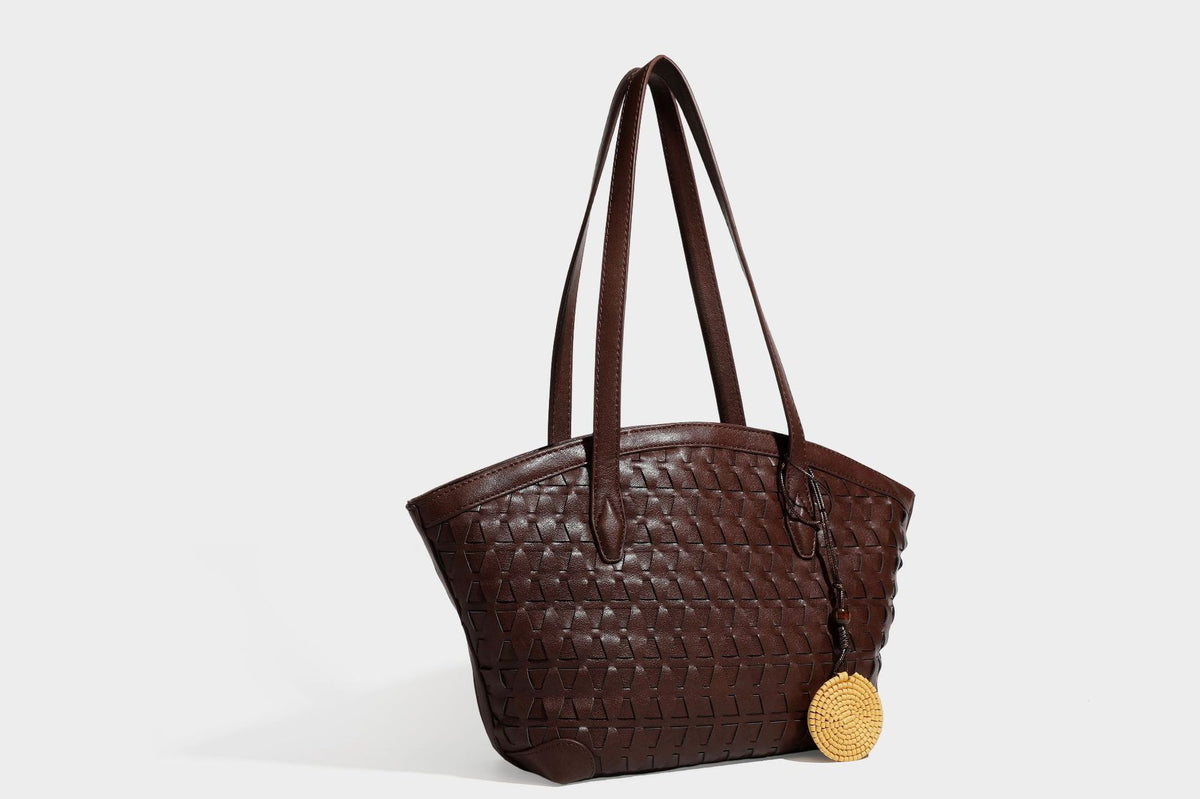 Large leather-look tote bag with geometric woven emboss, double shoulder straps, and round woven cord charm in brown, detail