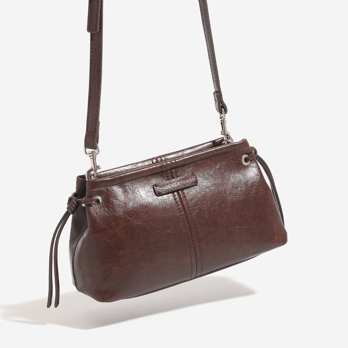 Small retro convertible shoulder bag with glossy leather-look finish, side drawstring ties, top zip closure, and silver-tone