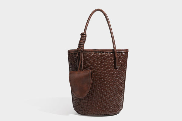 Structured woven-texture leather-look bucket bag in brown with knotted top handles, small front flap pouch, and adjustable