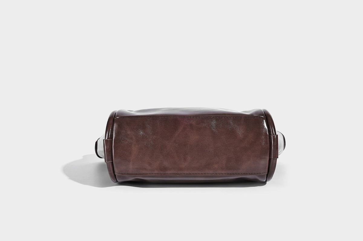 Glossy leather-look structured tote bag with rounded top handles, detachable shoulder strap, embossed front emblem, and side