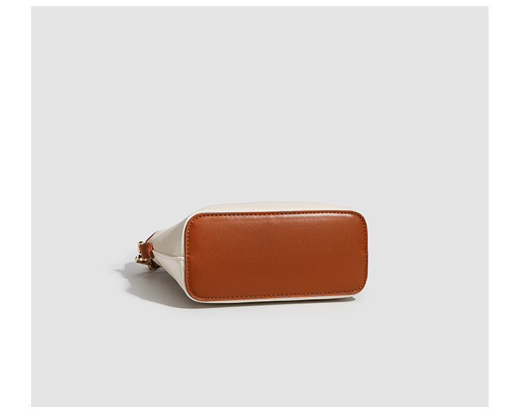 Kleine, formstabile Tote-Tasche mit Henkeln und Besatz in brauner Lederoptik auf einem cremefarbenen Korpus, Reißverschluss oben, goldfarbenen Nieten und