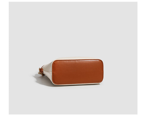 Kleine, formstabile Tote-Tasche mit Henkeln und Besatz in brauner Lederoptik auf einem cremefarbenen Korpus, Reißverschluss oben, goldfarbenen Nieten und