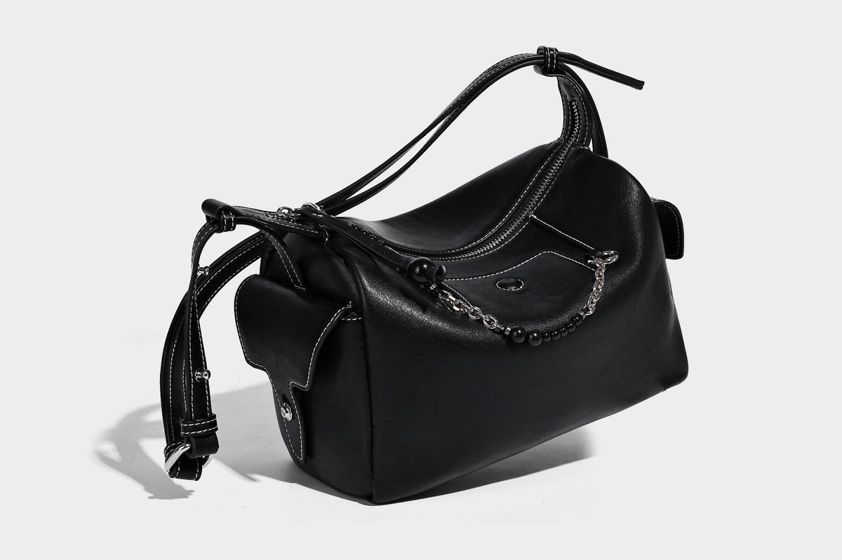Small slouchy moto-style crossbody bag in smooth matte leather-look finish with white contrast stitching, silver-tone, detail