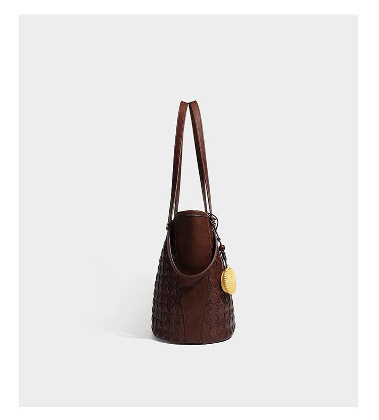 Brown embossed geometric woven leather-look bucket tote bag with dual shoulder straps, side snap hardware, and a round
