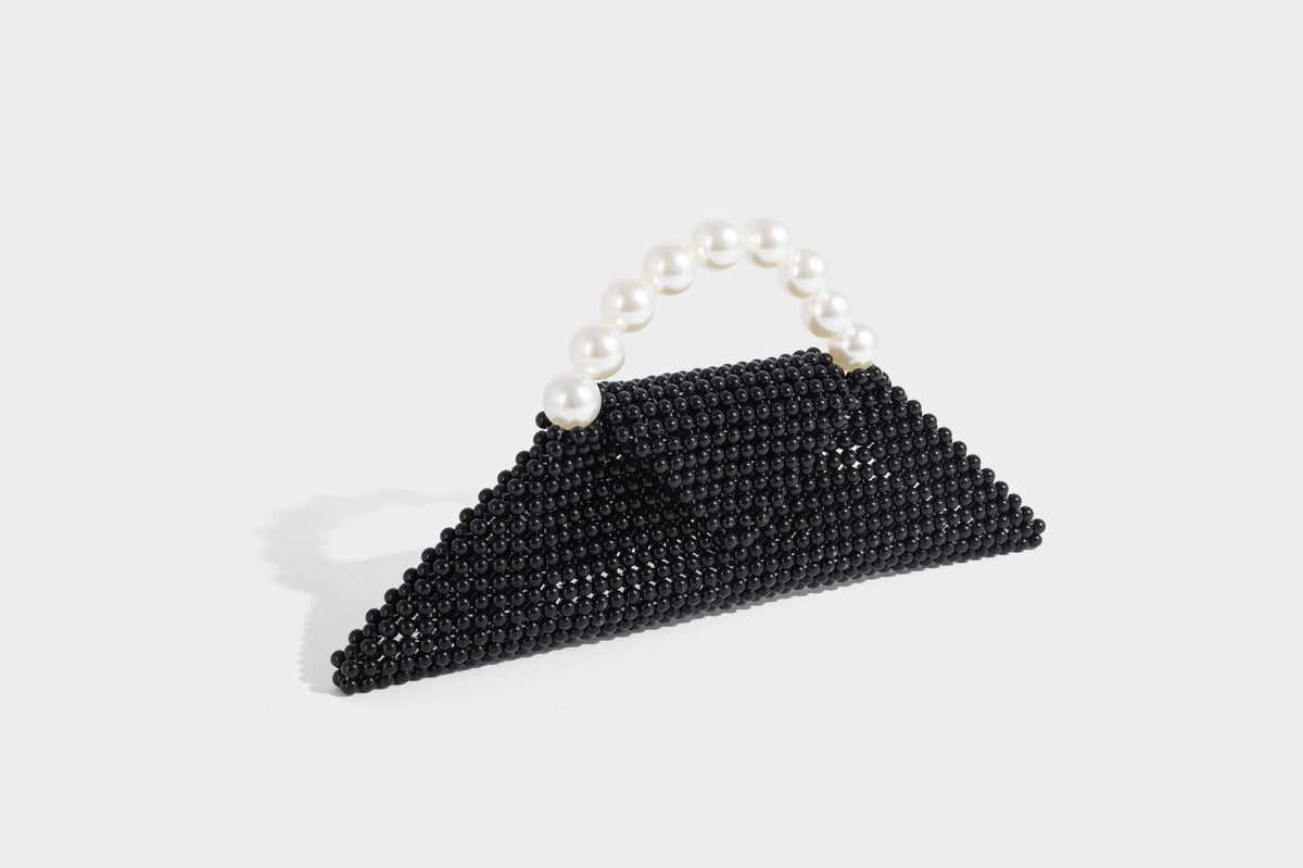 Small structured triangle clutch bag covered in glossy pearl beads with an arched pearl top handle and silver snap closure