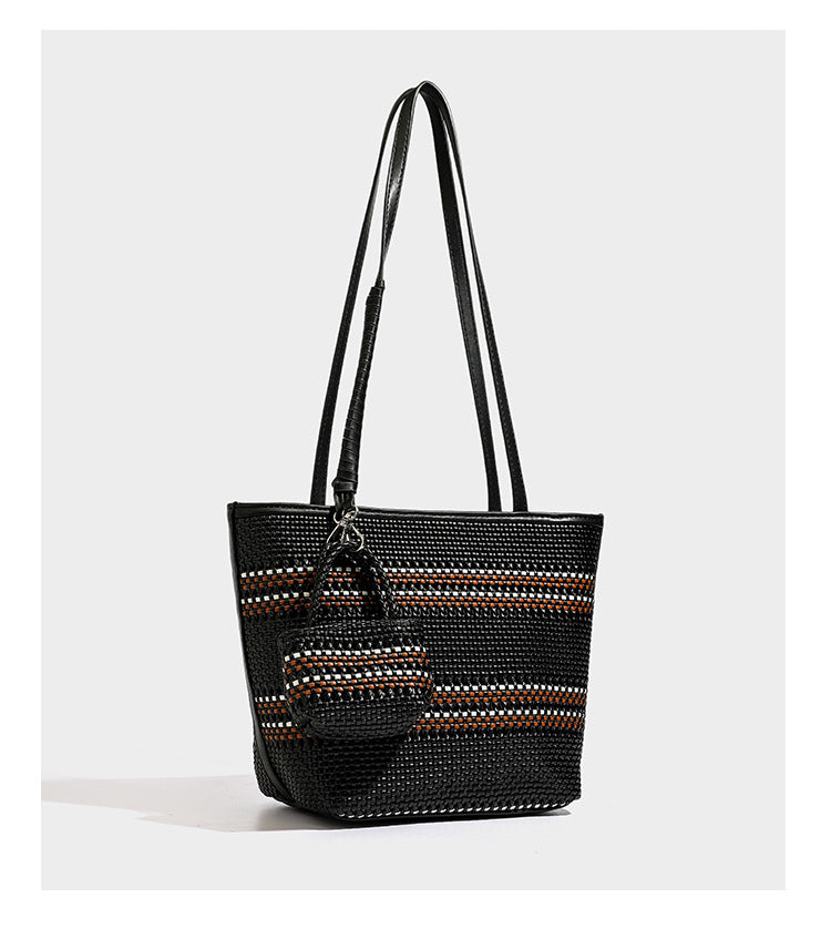 Large structured woven tote bag with striped basket-weave finish, long shoulder straps, and detachable mini pouch charm