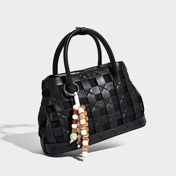 Small structured woven satchel tote with rounded top handles, silver-tone ring hardware, and bead tassel charm, detail view