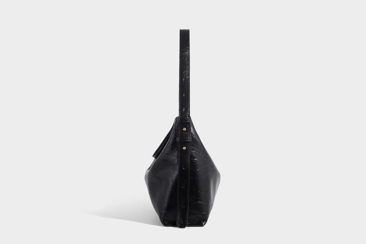 Large slouchy hobo shoulder bag in glossy crinkle leather-look finish with gold-tone emblem hardware and adjustable strap