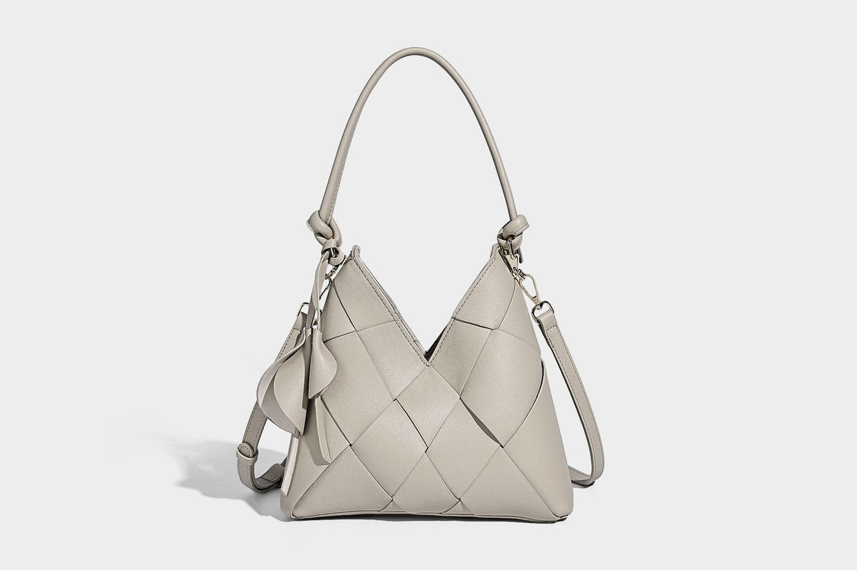 Compact bucket shoulder bag with black-and-white diamond patchwork panels, knotted top handle, gold-tone hardware, and