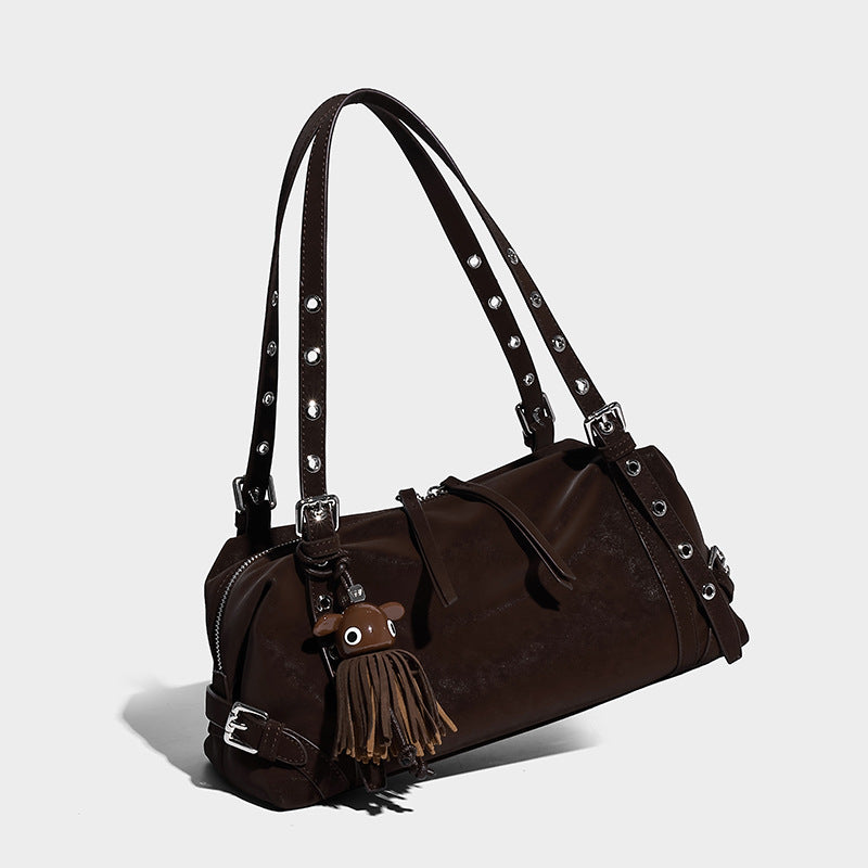 Slouchy barrel shoulder bag in dark brown with silver-tone grommet straps, top zip closure, side buckle hardware, and tassel