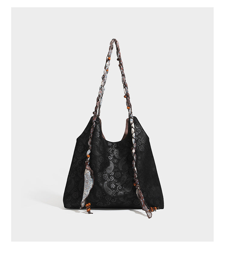 Slouchy paisley-embossed suede-look shoulder tote bag with braided patterned fabric straps and wood bead accents, detail view