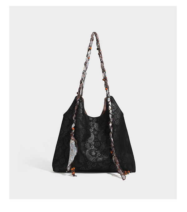 Slouchy paisley-embossed suede-look shoulder tote bag with braided patterned fabric straps and wood bead accents, detail view