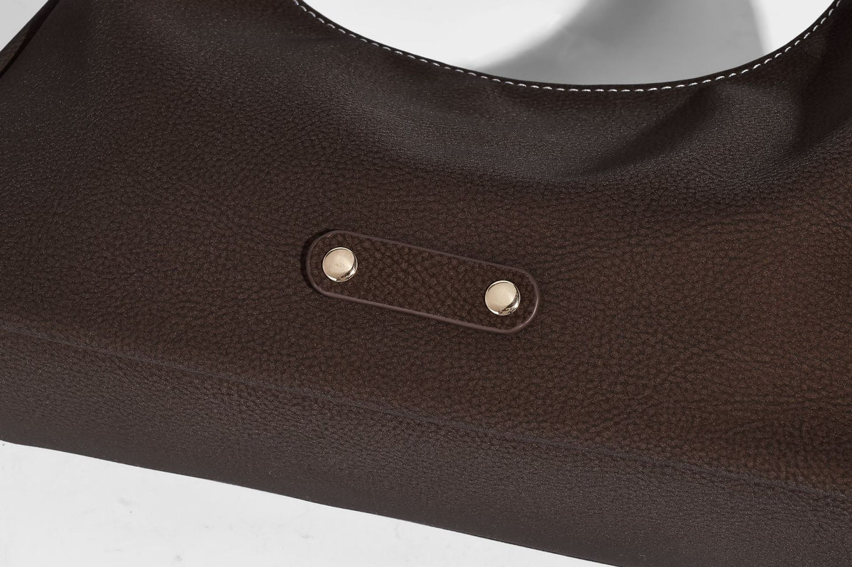 Crescent hobo shoulder bag in pebbled leather-look finish with top zipper, adjustable strap, gold-tone ring hardware, and
