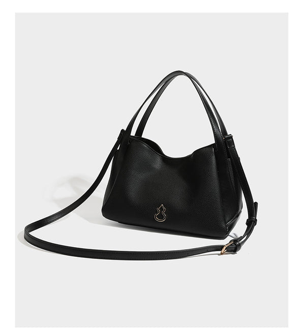 Schwarze Tote-Bag aus genarbtem Material in Lederoptik mit kürbisförmigen Beschlägen in Goldoptik, zwei Henkeln und abnehmbarem Umhängeriemen, Detailansicht