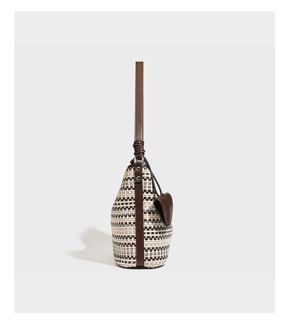 Woven stripe bucket shoulder bag in cream and dark brown with leather-look trim, knotted adjustable strap, and small shield