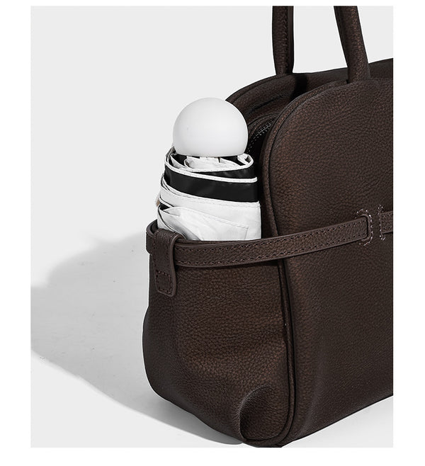 Strukturierte Henkeltasche aus mattem, genarbtem Material mit umlaufendem Riemen und Ringbeschlägen, zwei oberen Tragegriffen und abnehmbarem Crossbody-Riemen