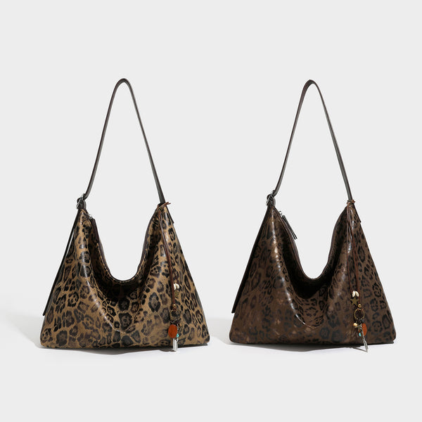 Slouchy leopard print hobo shoulder bag with glossy coated finish, top zipper closure, dark brown trim, and dangling charm