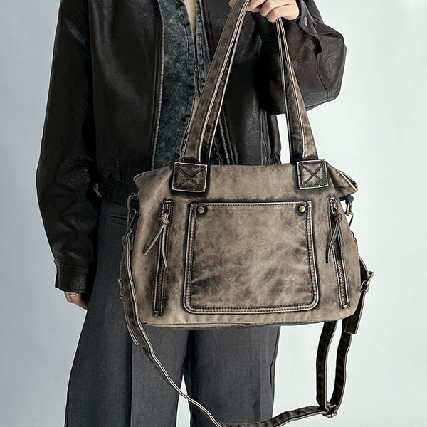 Distressed leather-look convertible tote bag with dual top handles, front zip and patch pockets, and adjustable shoulder