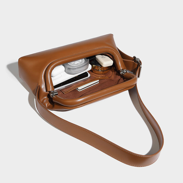 Compact structured baguette shoulder bag with smooth leather-look finish, zip top, and adjustable silver-buckle strap, detail
