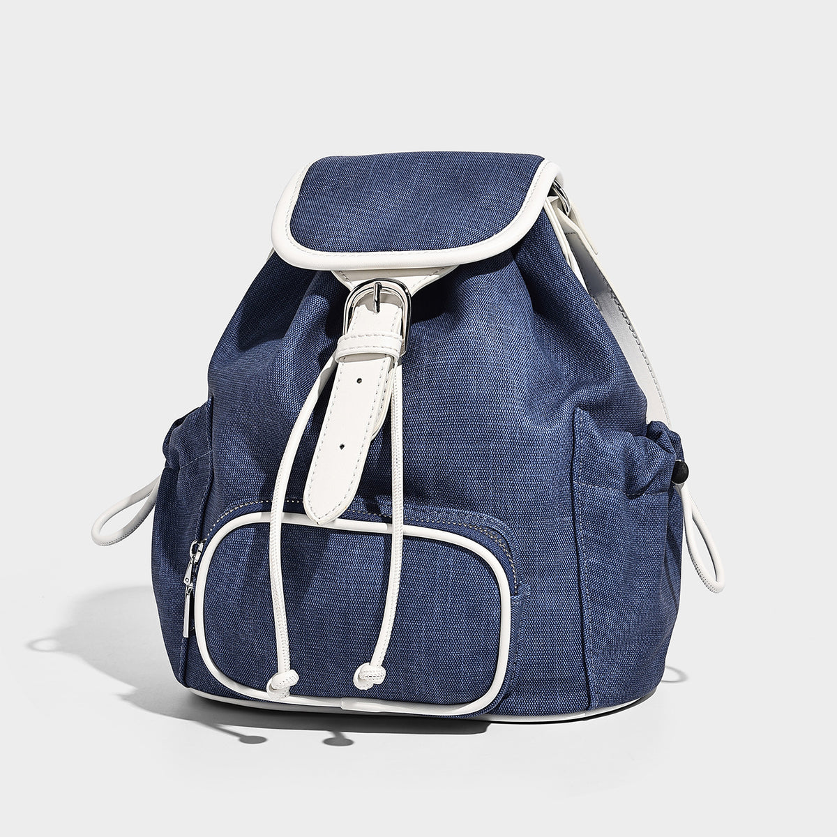 Compact denim drawstring backpack with white leather-look piping, flap-top buckle closure, front zip pocket, and silver-tone