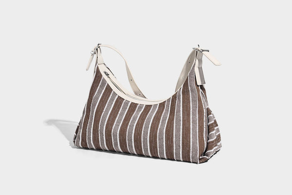 Weich fallende Hobo-Tasche aus gestreiftem Webmaterial mit kontrastierendem Besatz in Creme, Reißverschluss oben und verstellbarem Riemen mit Schnalle in Silberoptik, Detailaufnahme