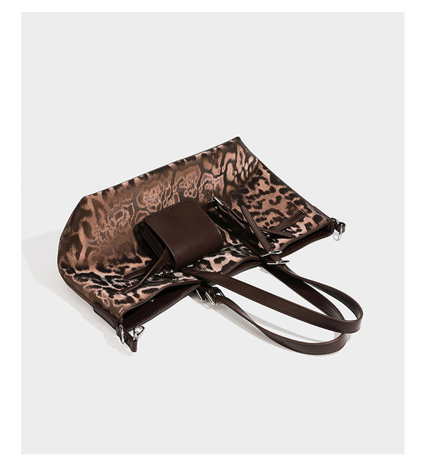 Glossy leopard-print tote bag with leather-look dark trim, dual top handles, detachable shoulder strap, and attached front