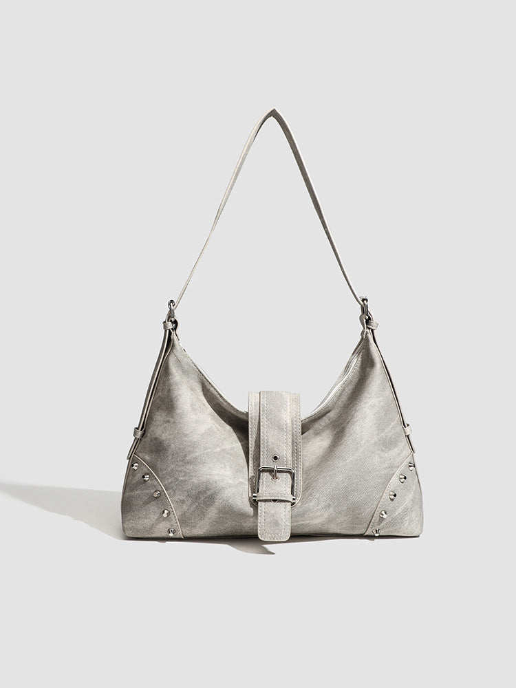 Slouchy trapezoid hobo shoulder bag with distressed textured finish, silver rivet corner accents, centre buckle strap, and