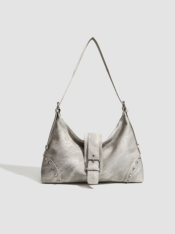 Slouchy trapezoid hobo shoulder bag with distressed textured finish, silver rivet corner accents, centre buckle strap, and