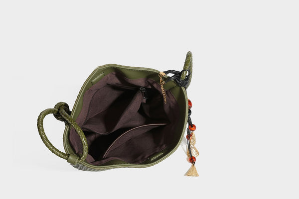 Olive green woven leather-look bucket bag with braided crossbody strap, knotted adjustment, and gold-tone tassel charm with