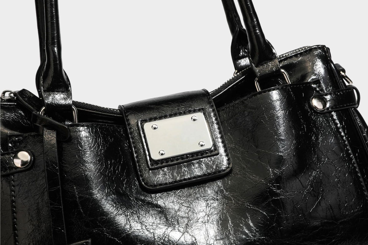 Structured glossy crinkled leather-look satchel with double top handles, front metal-plaque tab, silver-tone hardware, and