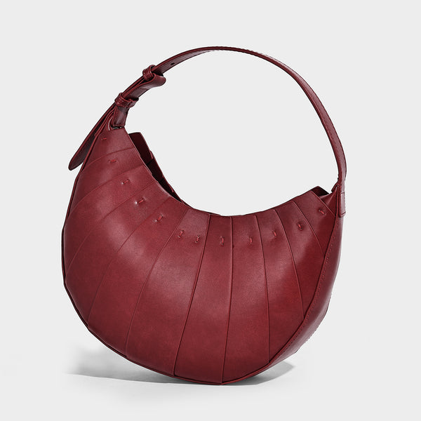 Crescent half-moon shoulder bag with vertical panel seaming, matte-satin leather-look finish, and adjustable gold-tone