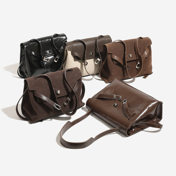 Structured trapezoidal flap satchel bag with silver-tone turn-lock clasp, decorative front strap tabs, gusseted sides, and
