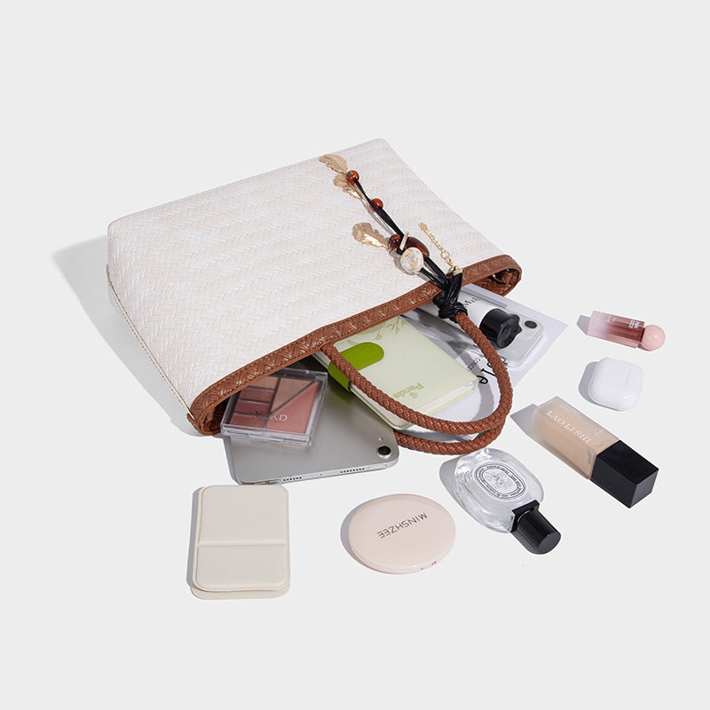 Structured woven-texture tote bag with brown braided top handles, decorative tassel charm, and detachable shoulder strap