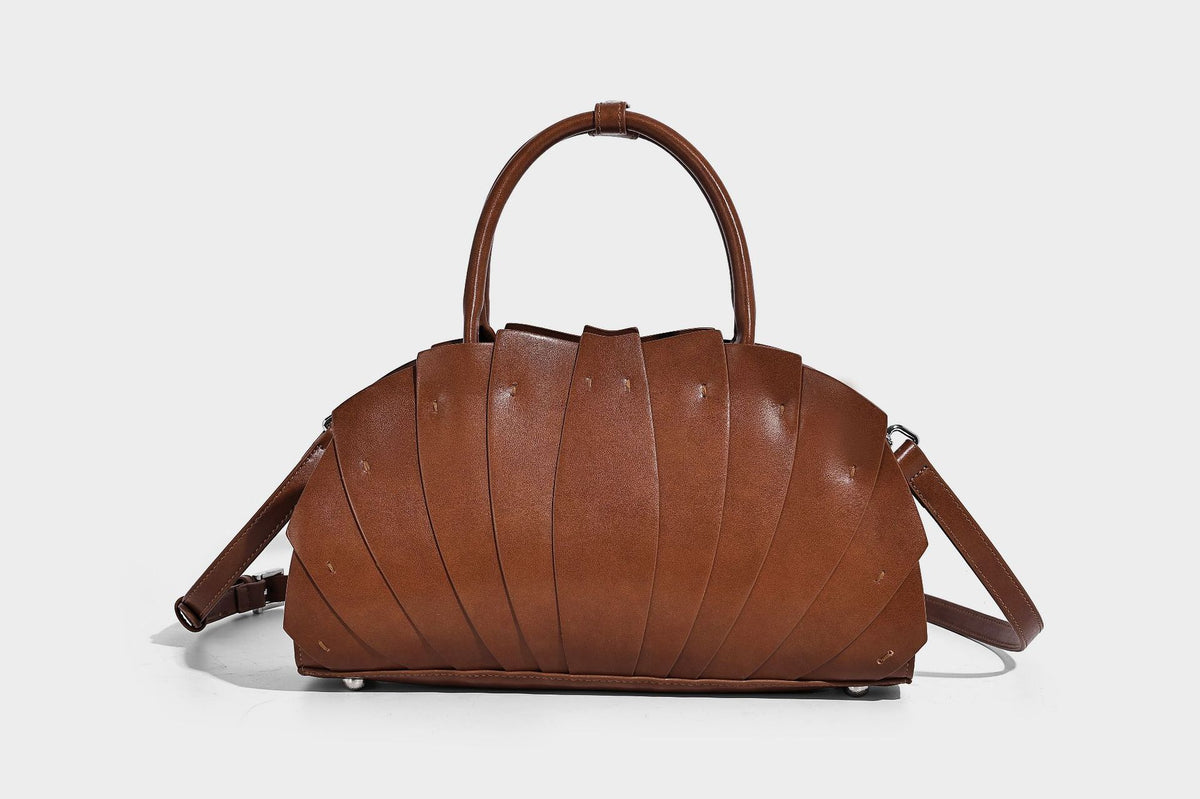 Structured dome satchel with fan-pleated leather-look exterior, dual top handles, and detachable shoulder strap, detail view