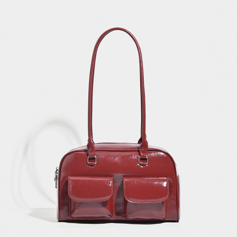 Structured glossy leather-look bowling shoulder bag with two front flap pockets, top zip closure, and long double shoulder