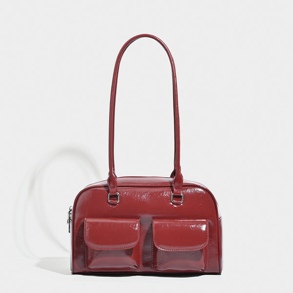 Structured glossy leather-look bowling shoulder bag with two front flap pockets, top zip closure, and long double shoulder