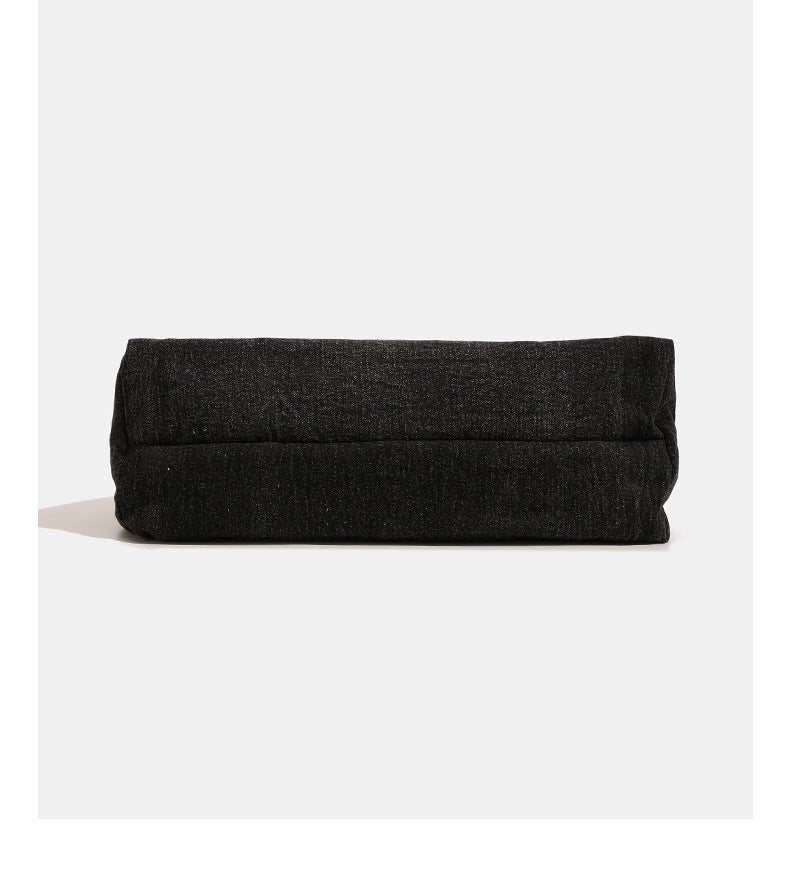 Oversized slouchy black textured canvas hobo shoulder bag with zip-top closure and adjustable dark-hardware strap, detail
