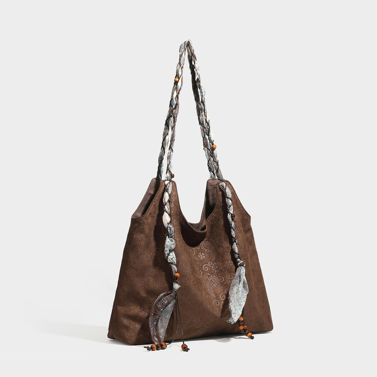 Slouchy paisley-embossed suede-look shoulder tote bag with braided patterned fabric straps and wood bead accents, front view