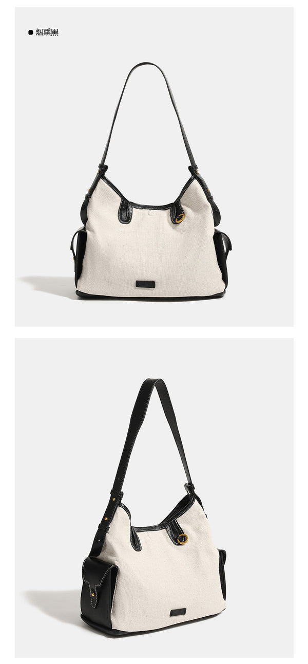 Off-white canvas hobo shoulder bag with black leather-look trim, gold-tone ring hardware, top zip closure, side pockets, and