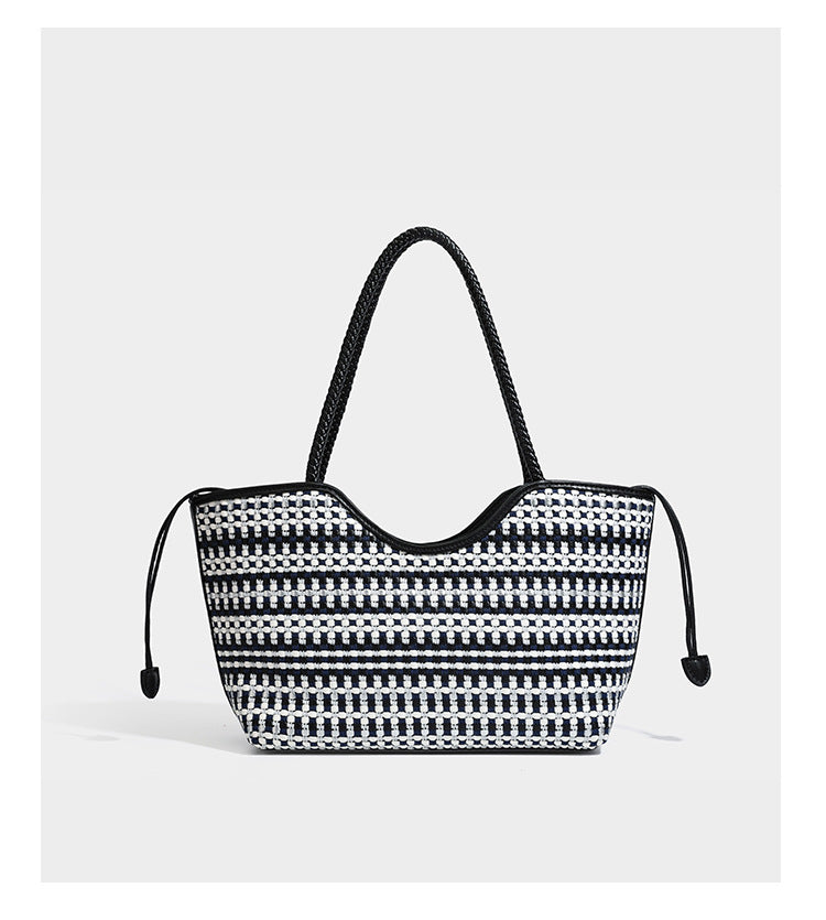 Large woven checker-pattern tote bag with dark braided shoulder straps, leather-look trim, and drawstring side ties, detail